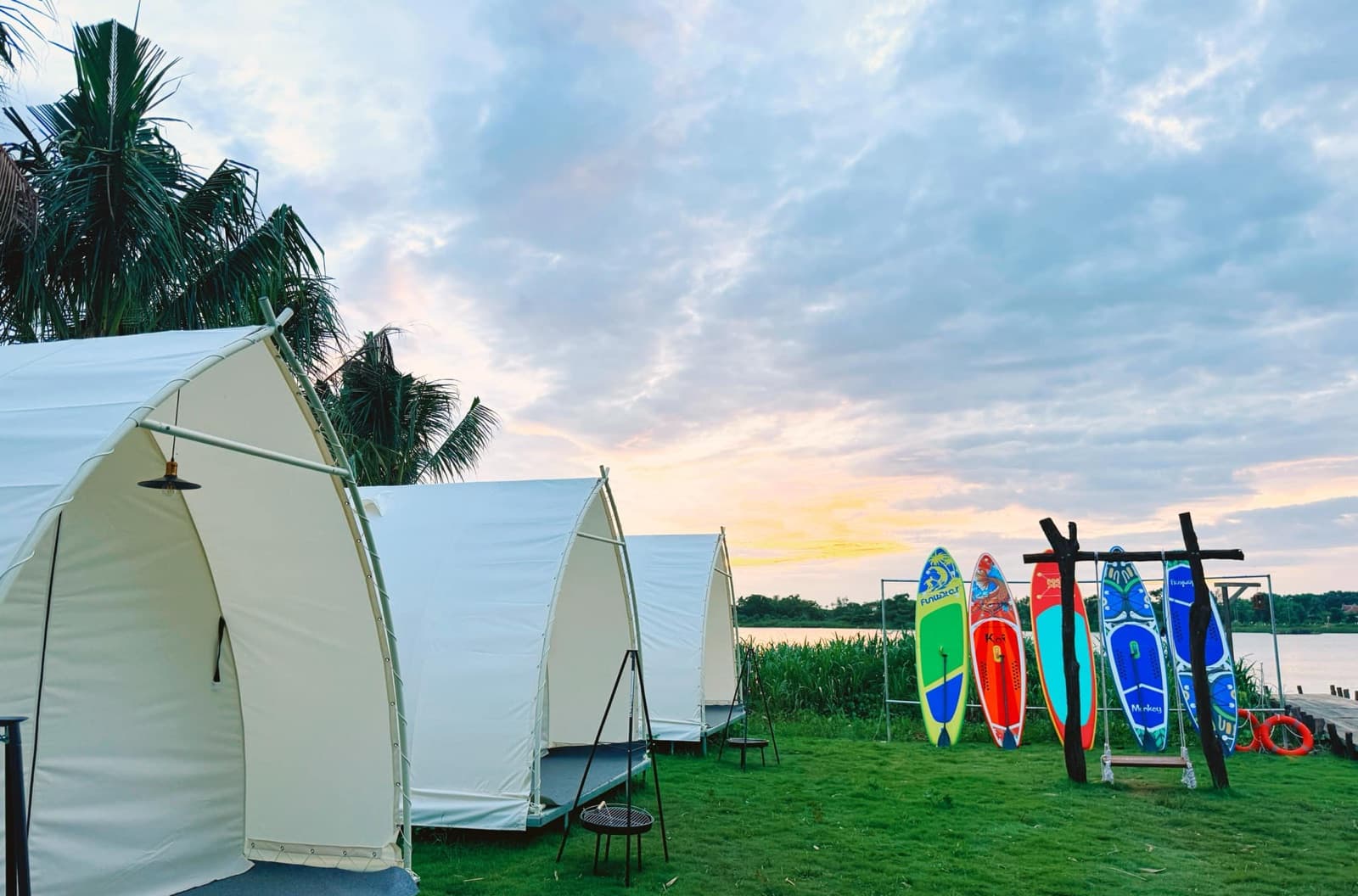Lều glamping ven sông lúc hoàng hôn — Ván SUP dựng bên bờ